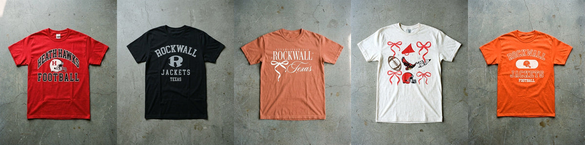 Five Pearl and Pennant spirit tees laid flat on concrete in a row, Heath Football Red Zone in red, Rockwall Arched Basic in black, Rockwall Bow So Cute in terracotta, Heath Spirit Checkered in natural and Rockwall Old School in orange