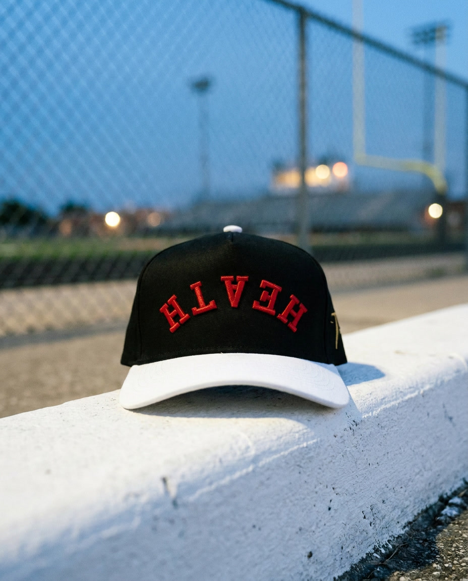 BKWHRD Heath upside down hat, black crown, white brim, red embroidery, on a painted curb at blue hour in Rockwall Texas
