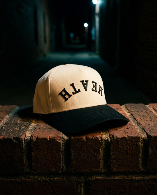 CRBKBK Heath upside down hat, cream crown, black brim, black embroidery, on a brick ledge at night in Rockwall Texas