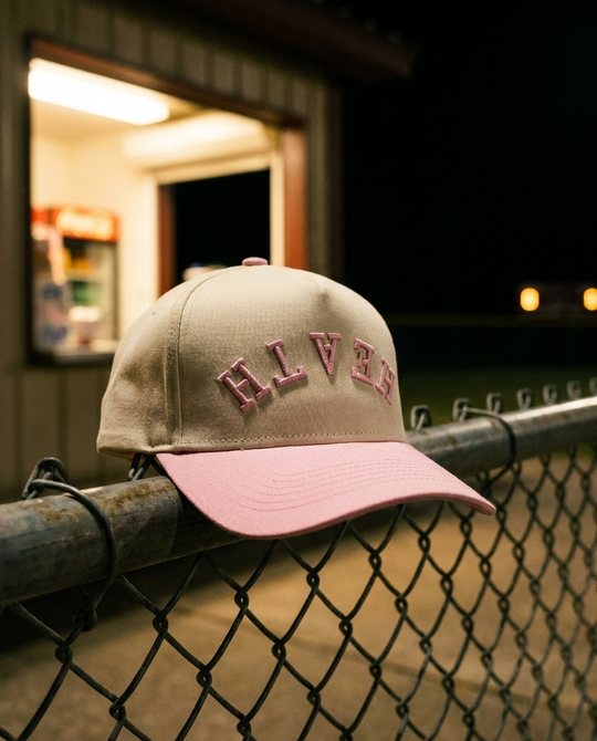 CRPKPK Heath upside down hat, cream crown, pink brim, pink embroidery, on a fence rail by the concession stand in Rockwall Texas