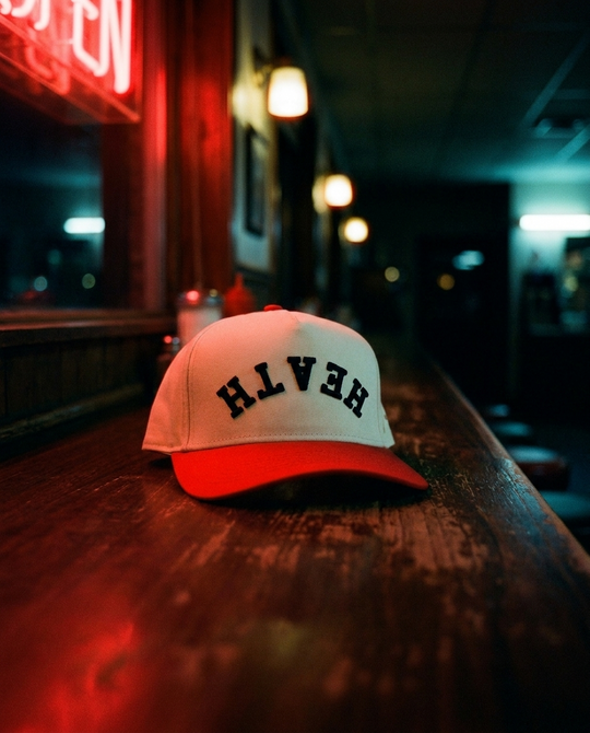 CRRDBK Heath upside down hat, cream crown, red brim, black embroidery, on a diner counter at night in Rockwall Texas