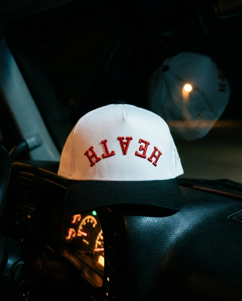 WHBKRD Heath upside down hat, white crown, black brim, red embroidery, on a truck dashboard at night in Rockwall Texas