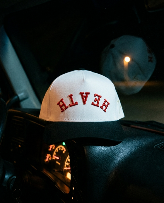 WHBKRD Heath upside down hat, white crown, black brim, red embroidery, on a truck dashboard at night in Rockwall Texas